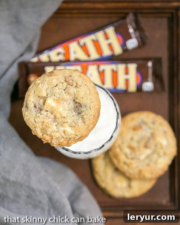 White Chocolate Toffee Chunk Cookies - oatmeal cookies chock full of deliciousness! White Chocolate Toffee Chunk Cookies on a glass of milk with Heath bars and a gray napkin