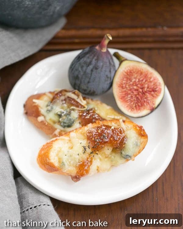 Artisan Fig Gruyere Crostini 2 Fig Gruyere Crostini on a white appetizer plate with fresh figs.
