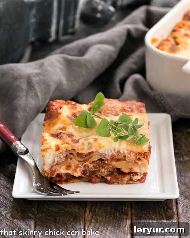A perfectly sliced piece of Sausage Ricotta Lasagna on a white plate, garnished with a fresh sprig of oregano.