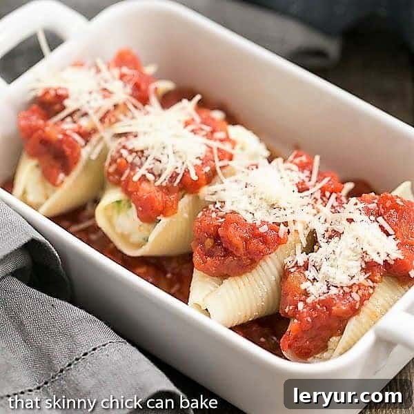 A large baking dish filled with spinach and ricotta stuffed pasta shells, generously coated in marinara sauce and topped with shredded cheese, ready to be placed in the oven for baking.