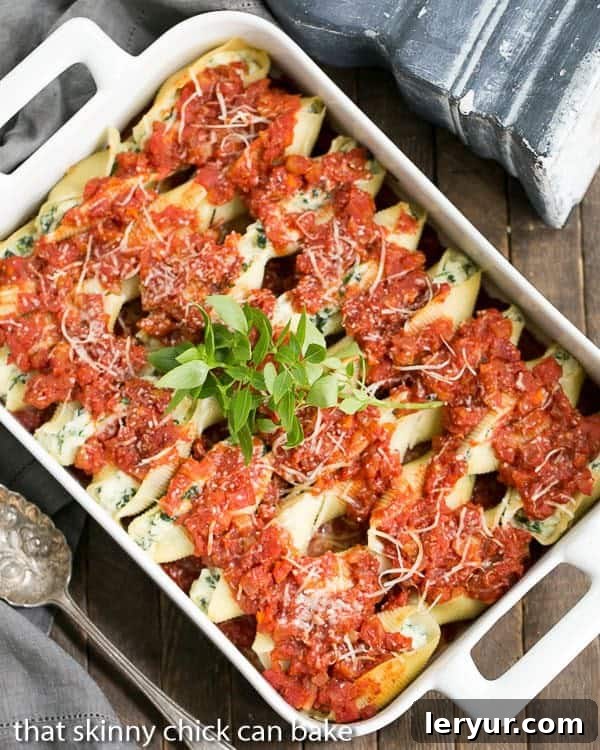 Close-up of golden-brown spinach and ricotta stuffed pasta shells in marinara sauce, garnished with fresh parsley, in a baking dish.