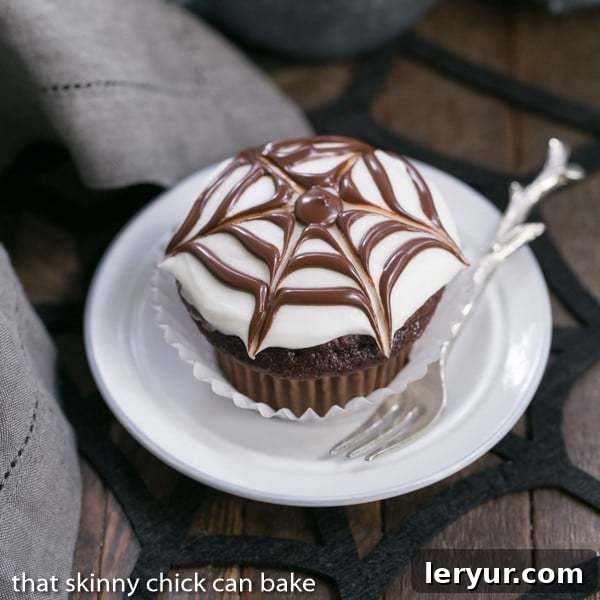 Spiderweb Cupcake on a white dessert plate with a silver fork, perfect for Halloween treats.