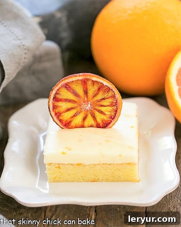 Orange Cake with Cream Cheese Frosting - An exquisite, dense, frosted orange cake Orange Cake with Cream Cheese Frosting on a square white plate with oranges
