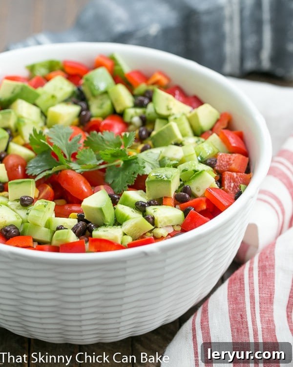 Tex-Mex Fiesta Salad - A veggie packed Tex-Mex Salad with a honey lime dressing Fiesta Salad in a white ceramic bowl next to a white and red striped tea towel