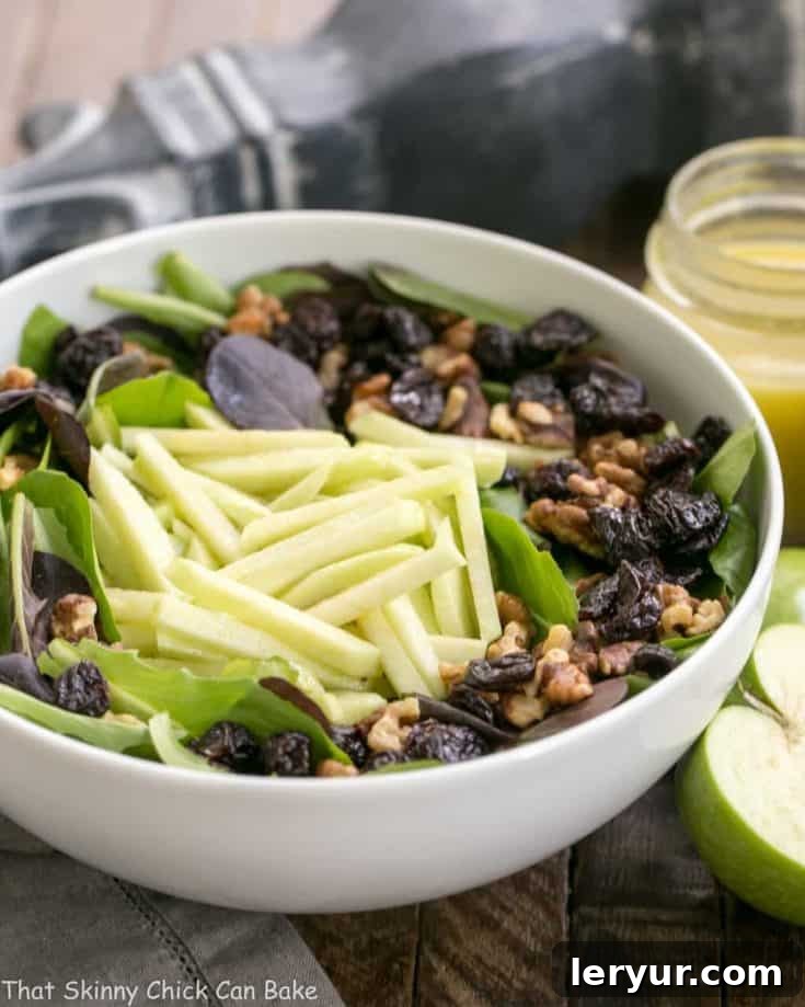 A fresh salad with red apples, dried cherries, and walnuts, drizzled with a maple dressing.