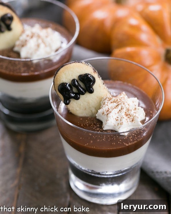 Midnight Graveyard Parfaits 2 Luscious Fudgy Tombstone Parfaits with layers of Oreo crumbs, creamy cheesecake filling, and rich fudge sauce, topped with a Milano cookie tombstone, ideal for a Halloween party.