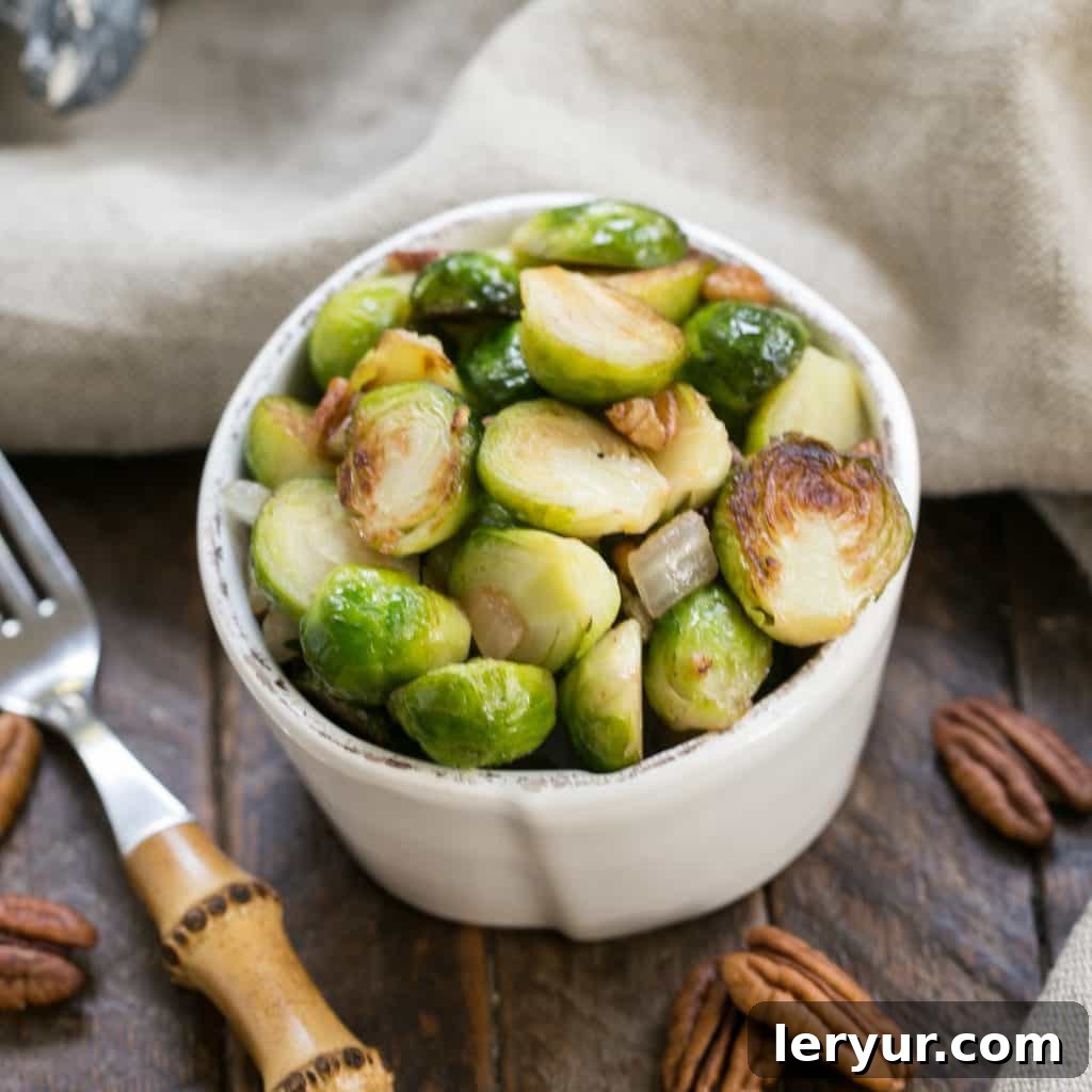 Overhead view of a small white bowl of golden-brown sautéed Brussels sprouts, ready to be served.