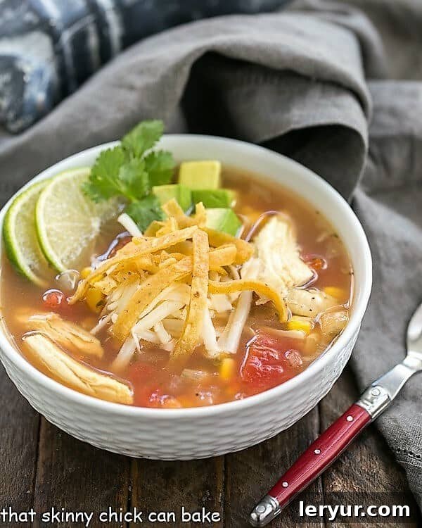Leftover Turkey Tortilla Soup - A refreshing and hearty meal using turkey leftovers! A serving of Leftover Turkey Tortilla Soup in a white bowl, beautifully garnished with fresh lime wedges and cilantro sprigs.