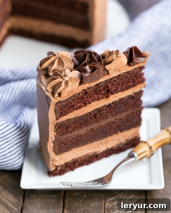 A beautifully presented slice of Chocolate Fudge Layer Cake on a square white plate, revealing perfectly defined layers of cake and frosting. This is undoubtedly one of the best chocolate cake recipes you'll ever taste!