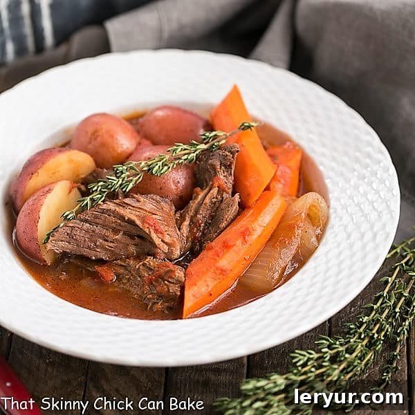 Easy Pot Roast - Slow cooked comfort food with beef, wine, tomatoes, carrots and potatoes Easy Pot Roast in a white bowl with thyme to garnish and thyme next to the bowl.