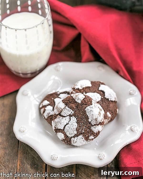 Chocolate Crackle Cookies - Fudgy cookies dusted in powdered sugar! Chocolate Crackle Cookies on decorative white plate.