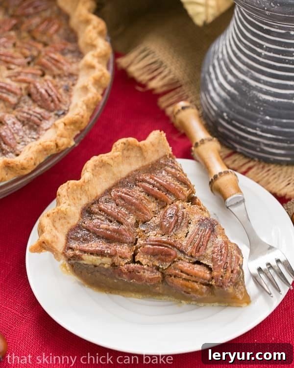 A beautifully presented Classic Pecan Pie, featuring a subtle boozy twist, rests on a white dessert plate beside a charming bamboo-handled fork, ready to be enjoyed.