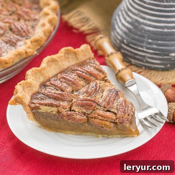 A delectable slice of Classic Pecan Pie, glistening with its rich, sweet filling and crunchy pecans, presented on a dessert plate atop a warm red woven napkin.