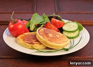 Two fluffy Matafan potato pancakes artfully arranged on a white plate alongside a vibrant mixed greens salad, ready to be enjoyed