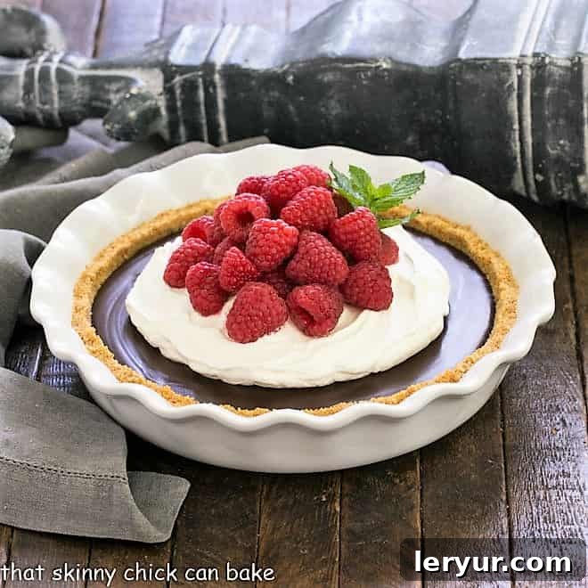 Dreamy Dark Chocolate Satin Pie, a rich and luscious fudgy custard topped with a cloud of whipped cream and fresh ripe berries.