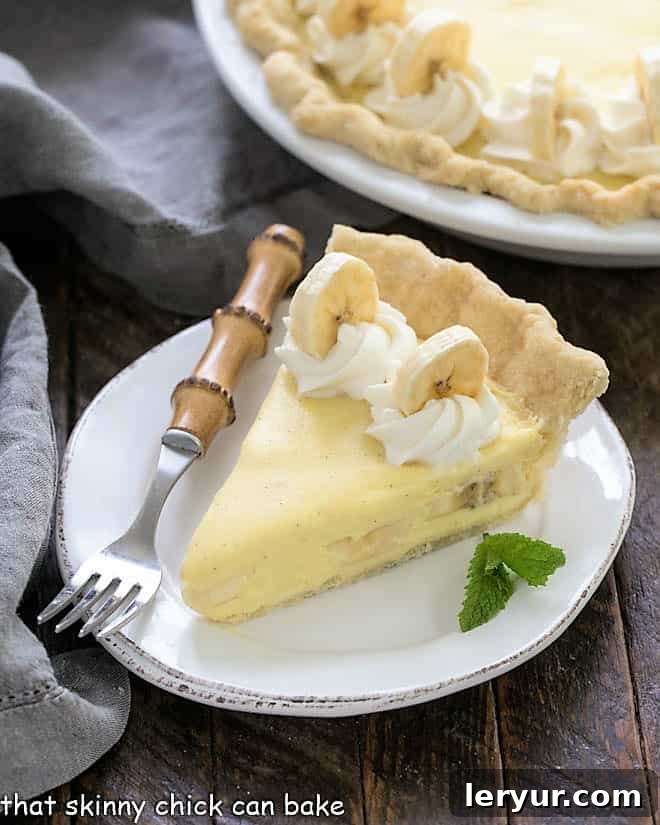 The Best Banana Cream Pie recipe, featuring a buttery pastry crust, creamy vanilla custard, fresh banana slices, and delicate whipped cream swirls.