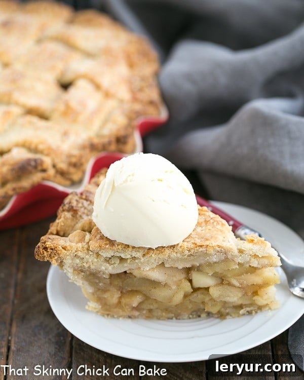Deep Dish Apple Pie - Packed full of precooked apples makes for a perfect autumnal pie! A slice of Deep Dish Apple Pie on a white dessert plate with a scoop of ice cream on top.
