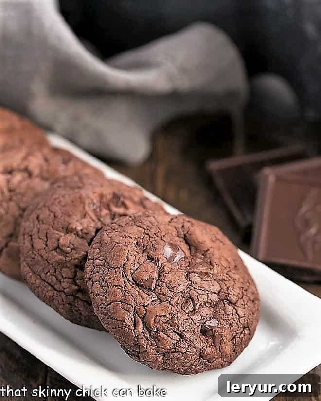 Black Gold Cookies - with two types of chocolate, chocolate chunks and minimal flour, these cookies are a chocoholic's dream! Black Gold Cookies lined up on a white rectangular tray