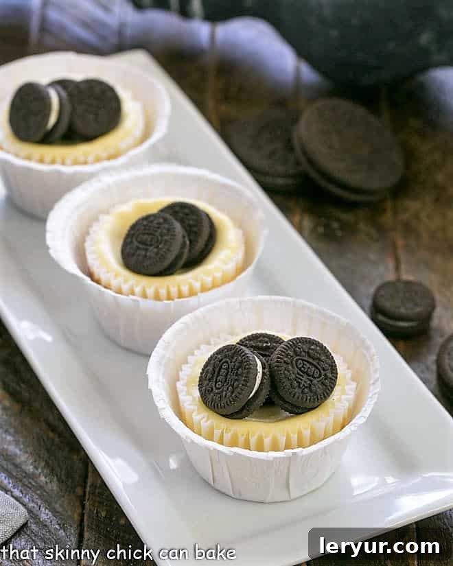 Mini Oreo Cheesecakes lined up on a white rectangular platter, ready to be served as individual desserts.