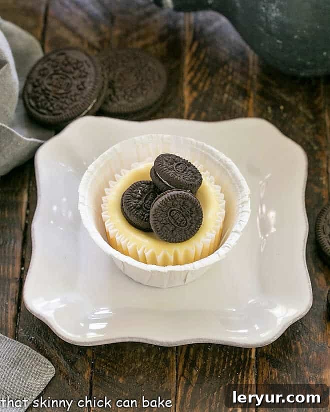 One Mini Oreo Cheesecake perfectly topped with three mini Oreos, presented on a square white plate, showcasing its delicious appeal.