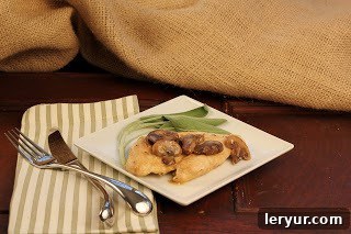 Velvety Marsala Chicken 2 Plate of chicken marsala with sage leaves on a green and white striped napkin, ready to be served.