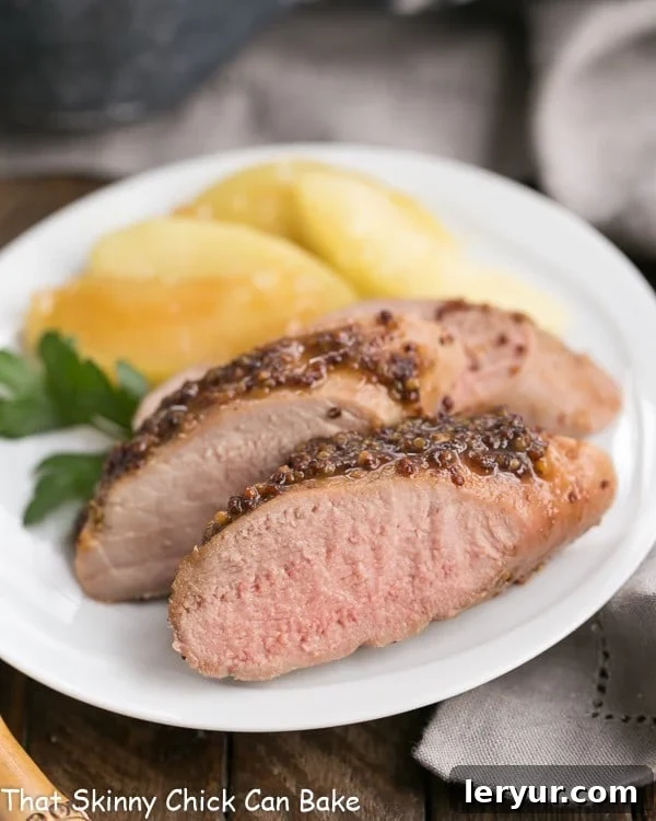Orchard Mustard Pork Tenderloin 2 Close up of a plate of apple mustard pork tenderloin with apple slices.