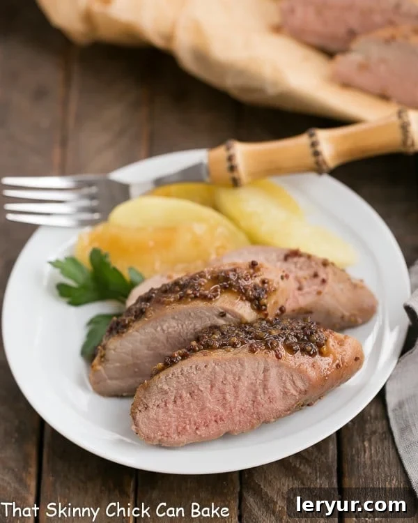 Orchard Mustard Pork Tenderloin 3 A plate of sliced apple mustard pork tenderloin with a bamboo handle fork.