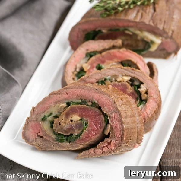 Flank Steak Roulades on a white rectangular tray, beautifully sliced to reveal the vibrant filling.