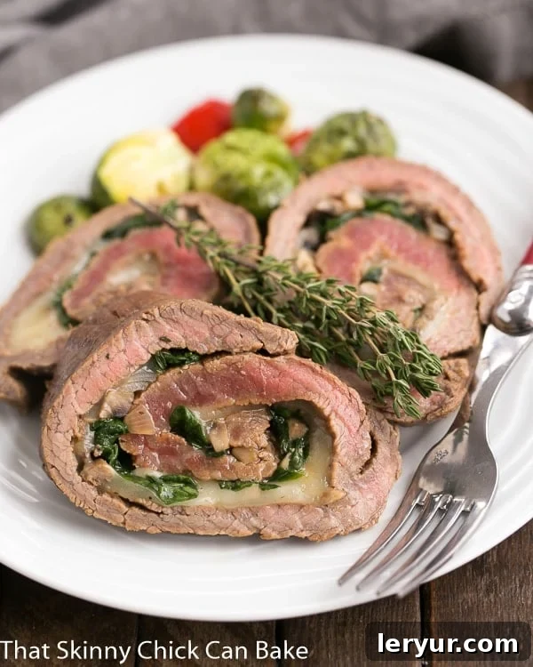 Flank Steak Roulades on a white dinner plate, garnished with fresh herbs.