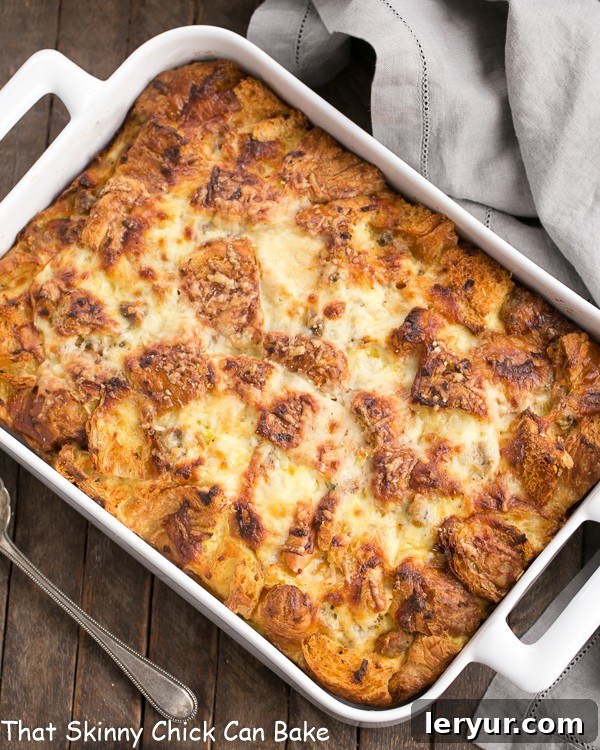Sausage Croissant French Toast Casserole - Tender, buttery and full of flavor from sausage, herbs and Gruyere, perfect for family brunch Overhead view of Sausage Croissant French Toast Casserole in a white baking dish, garnished with fresh sage.