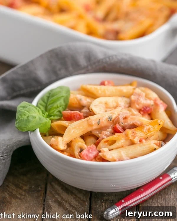 Cheesy Baked Pasta in a white bowl garnished with fresh basil