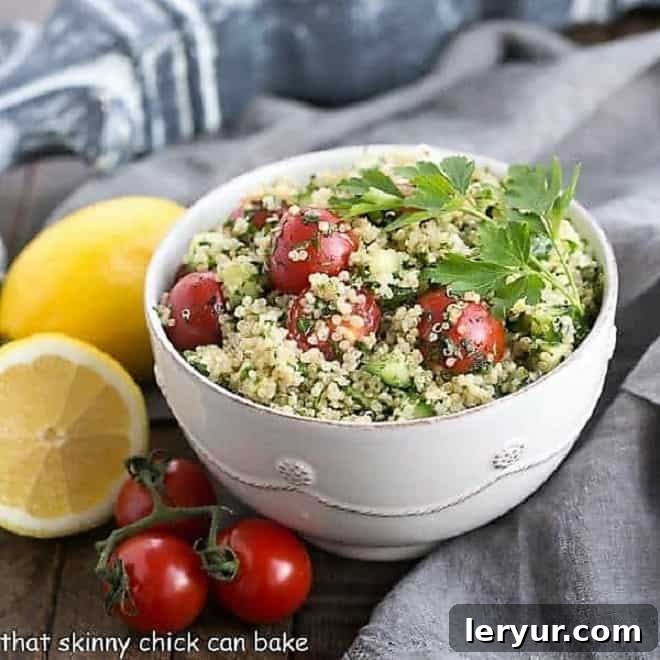 A close-up of a white bowl overflowing with Quinoa Tabbouleh, artfully arranged with a fresh lemon wedge and scattered cherry tomatoes, highlighting its freshness.