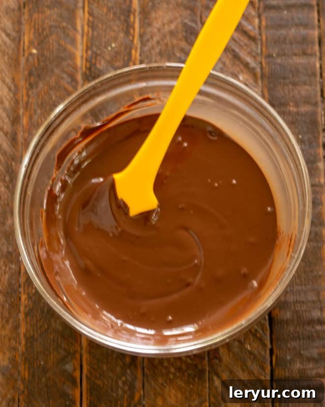 Melted semisweet chocolate cooling in a microwave-safe bowl, ready for the frosting preparation.