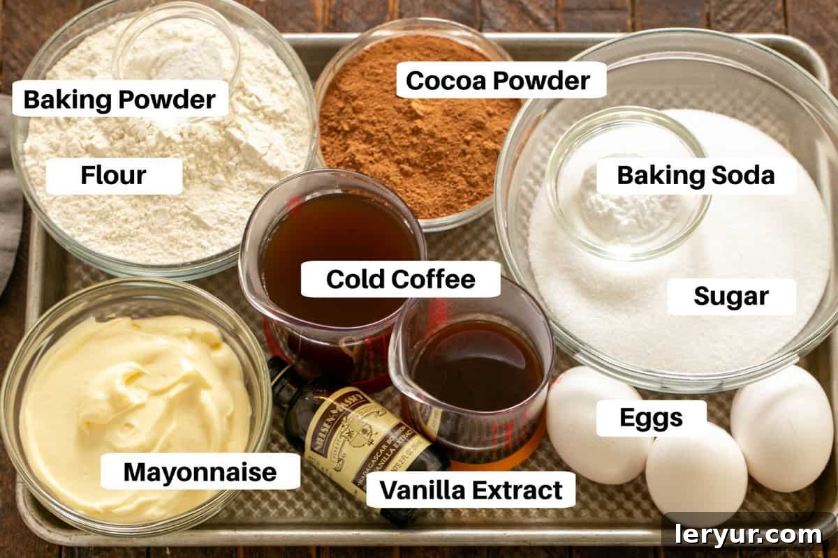 Assorted ingredients for Chocolate Mayonnaise Cake laid out on a metal sheet pan, with labels for clarity.