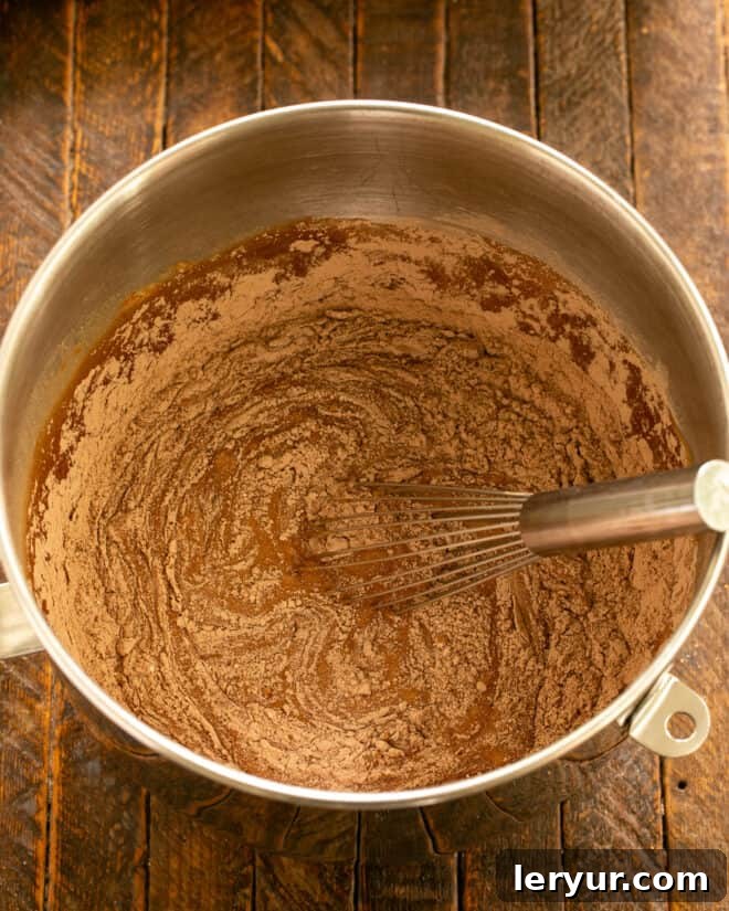 Whisking the cake batter until all ingredients are just combined and smooth, ensuring no lumps.