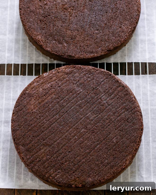 Baked chocolate cake layers cooling on wire racks after being removed from the oven and pans.