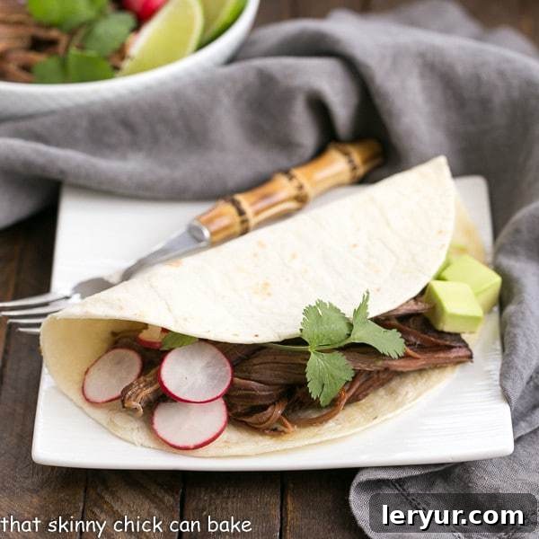 Slow Cooker Carne Asada - The classic Latin dish made in a slow cooker for maximum flavor and tenderness! Slow Cooker Carne Asada in a flour tortilla on a square white plate with a bamboo handle fork, ready to be enjoyed.