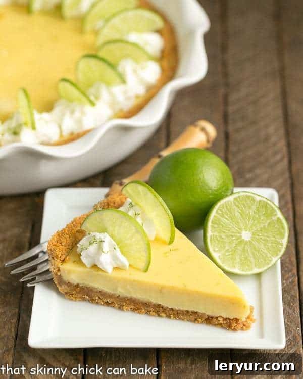 A perfectly cut slice of homemade Key Lime Pie, showcasing its vibrant green filling and thick graham cracker crust, served on a modern white dessert plate.