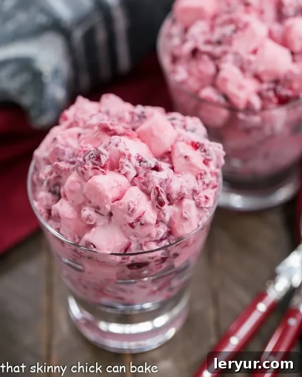 Individual servings of Cranberry Fluff Salad presented in elegant glass dishes, garnished with a fresh cranberry.
