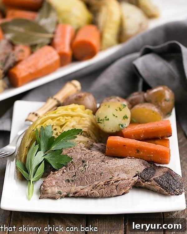 Braised Corned Beef and Cabbage starts with an uncured brisket flat instead of the already seasoned corned beef. Taking brisket, seasoning it and slow cooking with the traditional vegetables makes for an out of the ordinary St. Patrick's Day Irish corned beef and cabbage recipe! #stpatricksday #recipe #irishrecipe A beautifully plated Irish Braised Corned Beef and Cabbage dinner, showcasing tender beef slices, vibrant cabbage, carrots, and potatoes on a white plate, ready to be enjoyed.