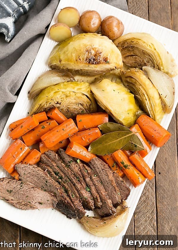 Braised Corned Beef and Cabbage starts with an uncured brisket flat instead of the already seasoned corned beef. Taking brisket, seasoning it and slow cooking with the traditional vegetables makes for an out of the ordinary St. Patrick's Day Irish corned beef and cabbage recipe! #stpatricksday #recipe #irishrecipe An overhead shot of a large platter generously laden with slices of Irish Braised Corned Beef, alongside perfectly cooked carrots, wedges of cabbage, and small round potatoes, creating a vibrant and appealing meal.