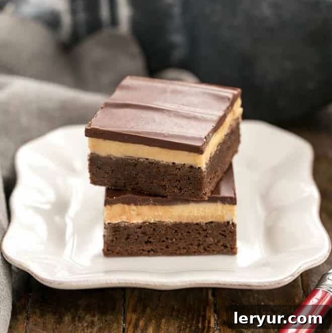 Peanut Butter Truffle Brownies - Fudgy brownies topped with a decadent peanut butter truffle filling and finished off with a dreamy chocolate ganache! A stack of three Peanut Butter Truffle Brownies on a white dessert plate, showcasing the thick, delicious layers of chocolate, peanut butter, and ganache.