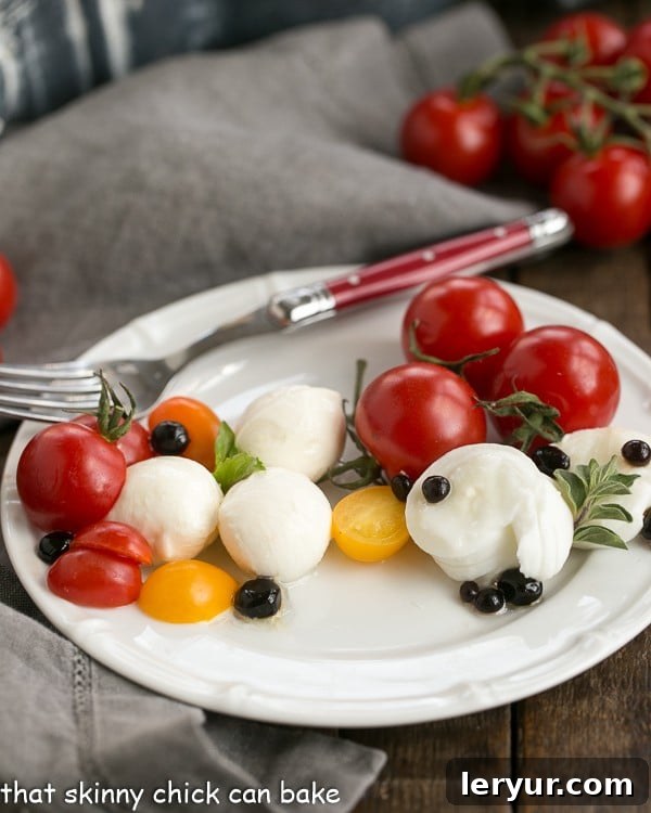 Side view of a Burrata Caprese Salad on a white plate with a fork