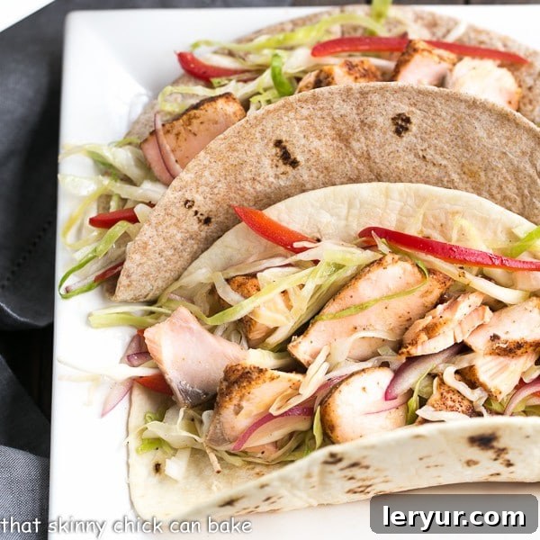 Best Fish Tacos Recipe with Mango Salsa - Roasted salmon with all the fixings for a sophisticated seafood taco Best Fish Tacos Recipe with Mango Salsa on a square ceramic plate. Roasted salmon tacos topped with fresh salsa and slaw.