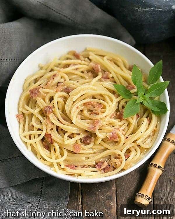 Overhead view of a beautiful bowl of Spaghetti Carbonara garnished with fresh basil.