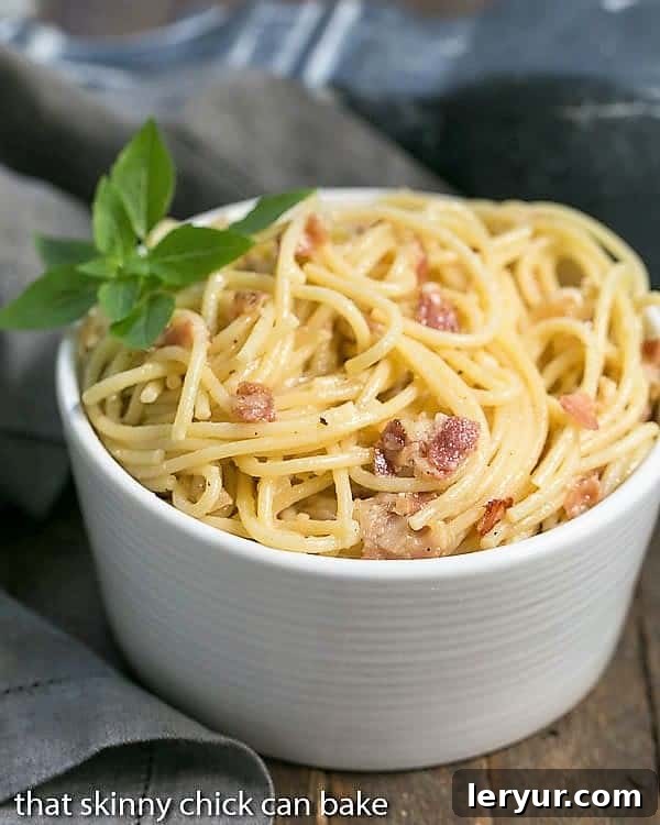 A close-up view of a ceramic bowl filled with creamy Spaghetti Carbonara, ready to be eaten.
