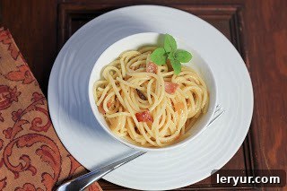 Overhead shot of a white bowl filled with creamy Spaghetti Carbonara, garnished and ready to eat.