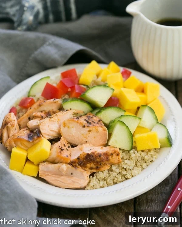 Caribbean Salmon Quinoa Salad - Perfectly portioned, healthy salad with quinoa, mangoes, jerk seasoned salmon and vegetables! Caribbean Salmon Quinoa Salad on a white plate