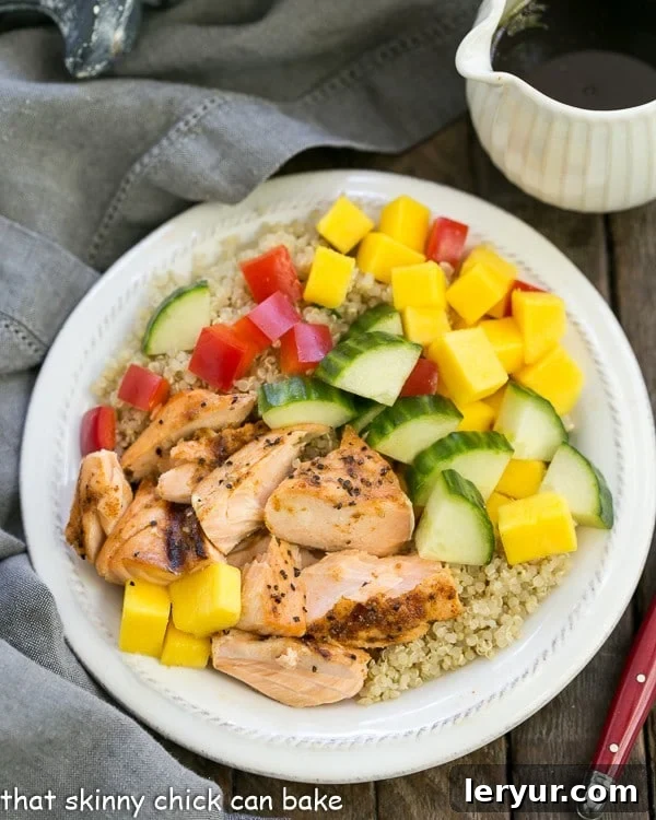 Caribbean Salmon Quinoa Salad - Perfectly portioned, healthy salad with quinoa, mangoes, jerk seasoned salmon and vegetables! Caribbean Salmon Quinoa Salad on a white salad plate with a red fork