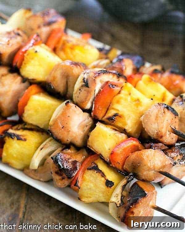 Honey Glazed Chicken Kabobs - Marinated chicken, veggies and pineapple are grilled to perfection! Skewered Honey Glazed Chicken Kabobs beautifully arranged on a white platter, ready to be served.